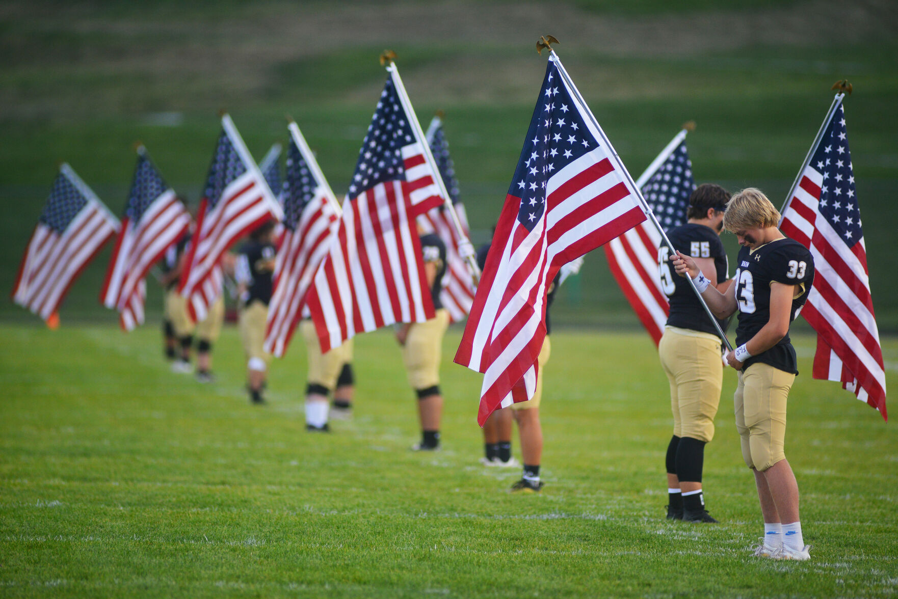 Bryce Camino joins 12 other teammates in holding American flags